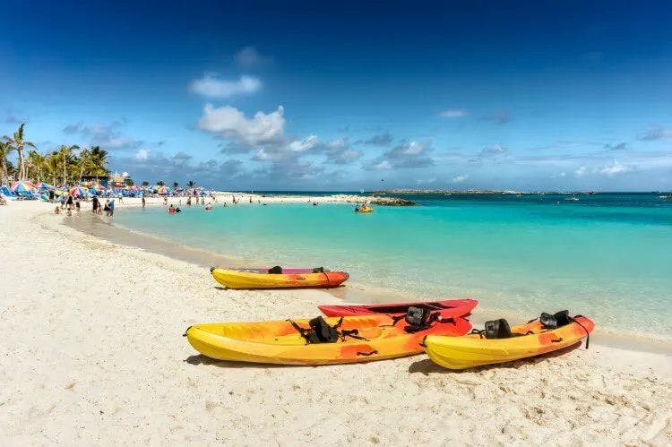Four yellow and orange kayaks on the white sand of a beach