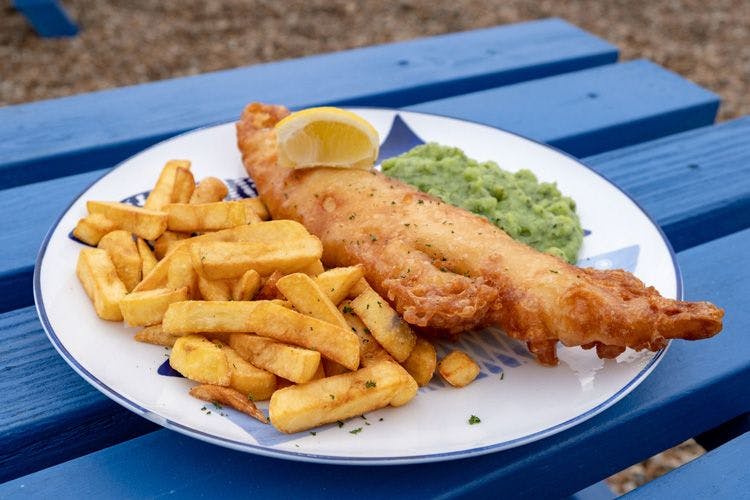 A plate of fish and chips on a blue wooden table