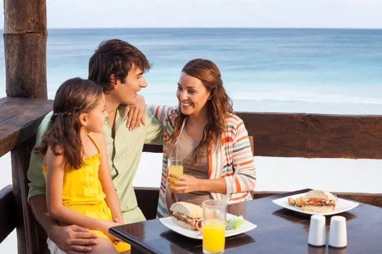 A family sits at a restaurant table by the sea