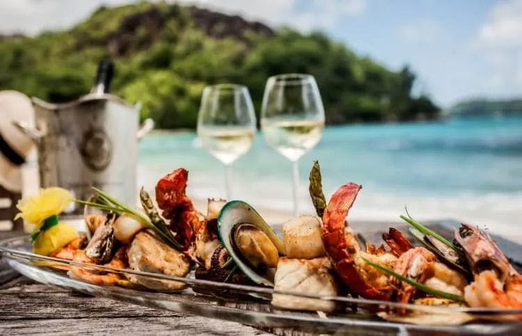 A seafood platter and wine glasses on a table by the sea