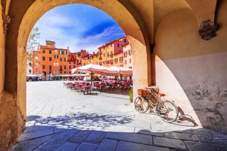 A bicycle rests against the wall of an arched doorway through to the central piazza of Lucca