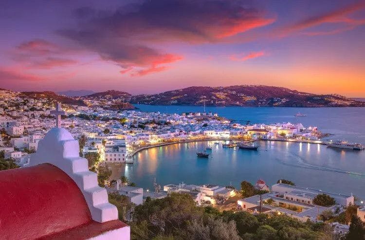 Sunset over Mykonos Town, with white sugar cube buildings lining the bay