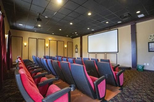 Movie theater with red and black chairs and large screen