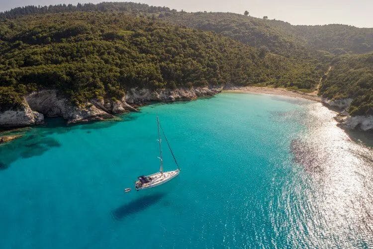 A sailboat in clear water off of the coast of Paxos