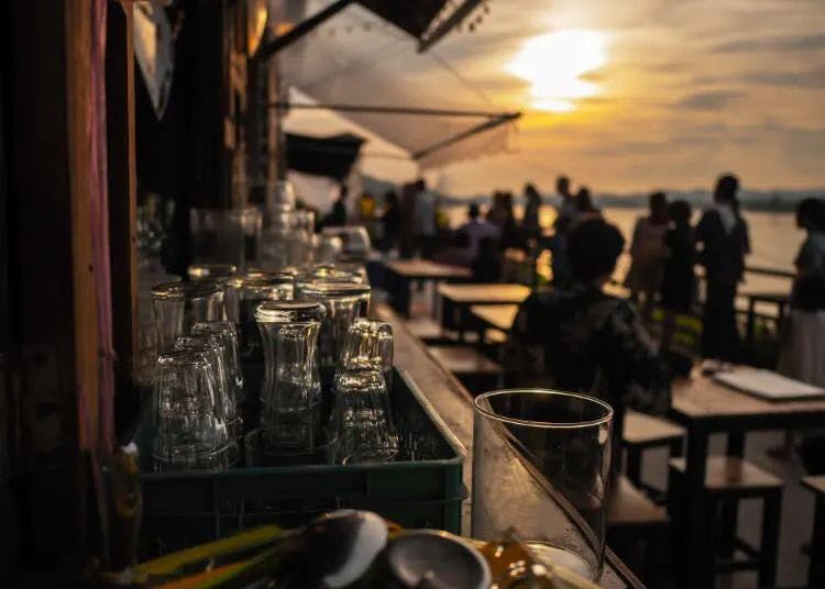 Sunset at a waterfront restaurant with glasses on a bar