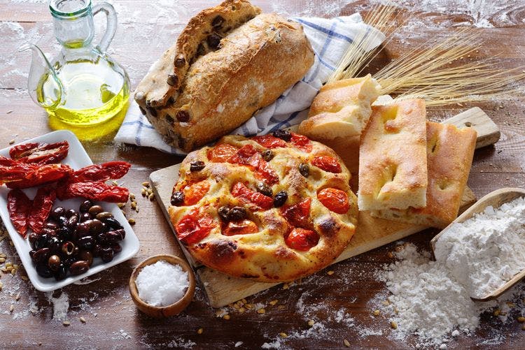 Table laid with focaccia, sundried tomatoes, olives, and olive oil