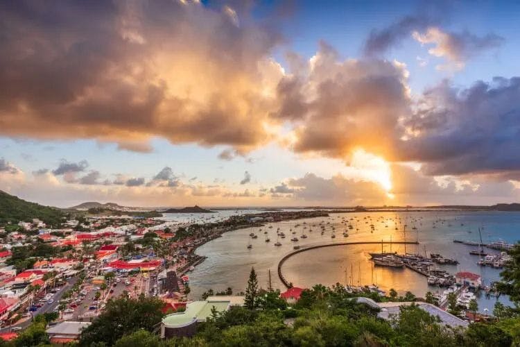 Sunset over a town and curved harbor in Saint Martin