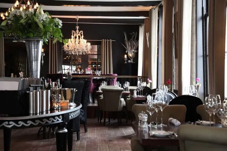 A posh restaurant with dark wood decor and candeliers