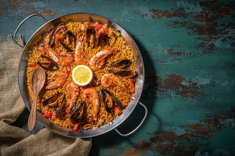 Paella pan with rice, mussels, prawns, and lemon