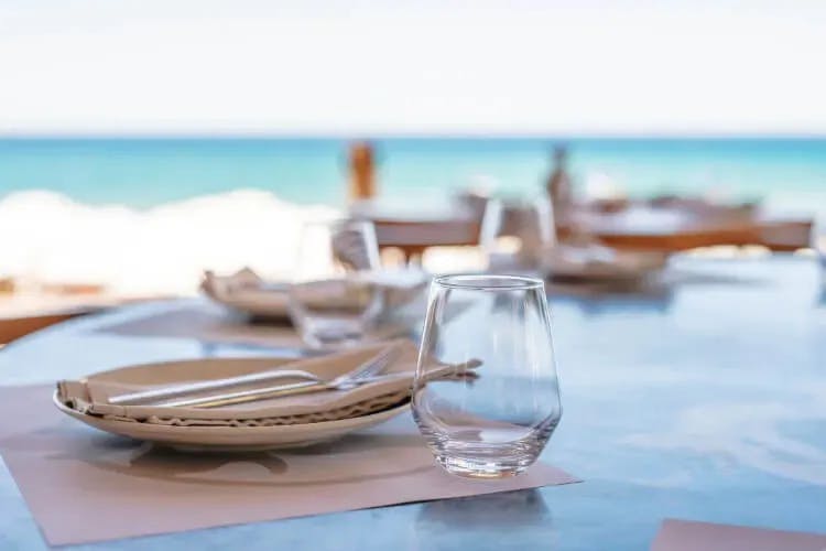 Restaurant table by the sea set with plates, cutlery and glass