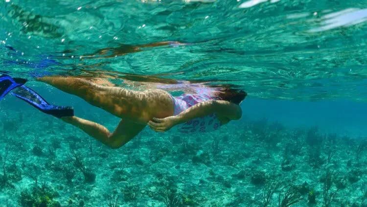 A woman snorkeling above a rocky reef