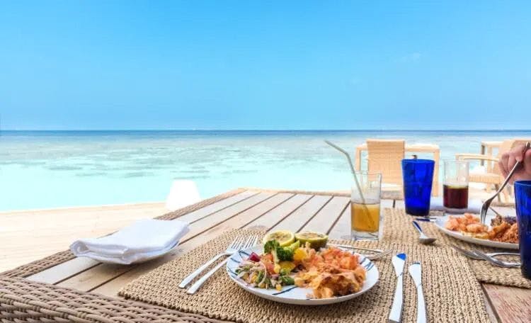 A plate of food on a table by the sea