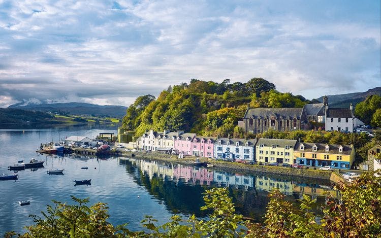 Pastel coloured buildings by a still harbor on the Isle of SKye.