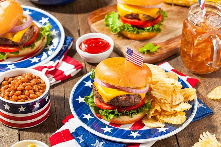 A spread of hamburgers, ice tea, and beans, on American flag plates