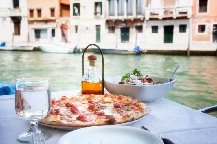 Pizza, salad and olive oil by a canal in Venice