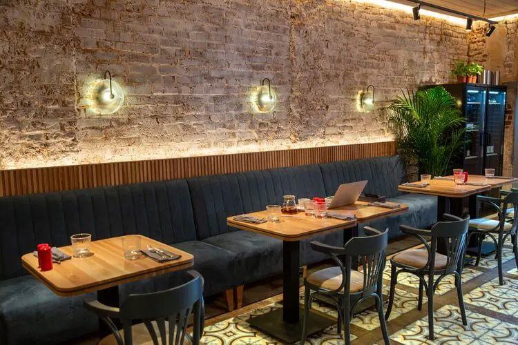 Restaurant interior with brick wall, black chairs, and oak table
