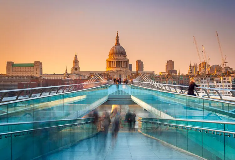 People walking across a bridge towards St Paul's Cathedral in central London