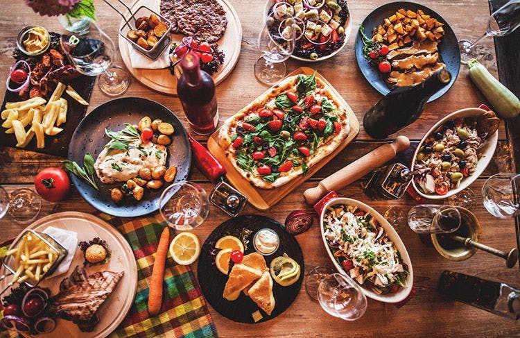A table full of different European dishes, including pizza, fish, and meats
