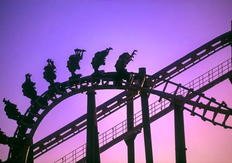 Silhouetted riders on a looping rollercoaster