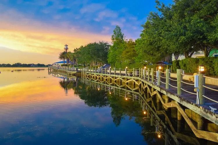 Boardwalk along the edge of a still lake in Orlando at sunset