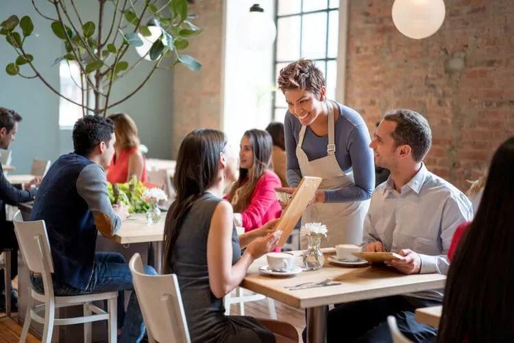 A waitress smiling as she take a couple's order at a restaurant