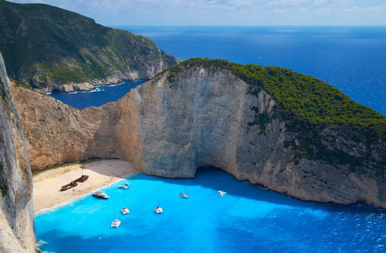 Shipwreck Beach in Zakynthos with a rusted ship on the shite sand surrounded by tall white cliffs