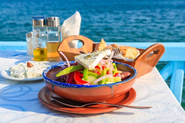 Greek salad and bread on a table by the ocean