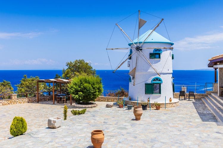 A white and blue windmill by the sea in Zante