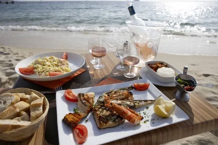 Plates of food and drinks on a table on a beach
