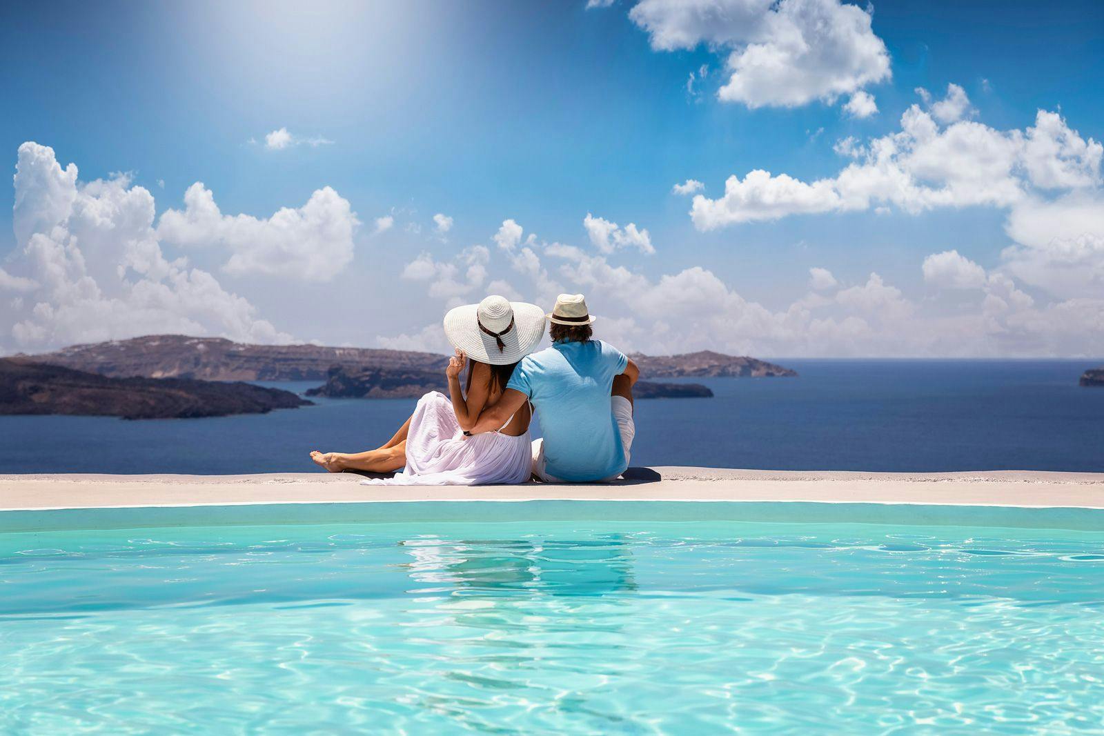 A couple sitting by a pool looking over the Aegean Sea in Greece