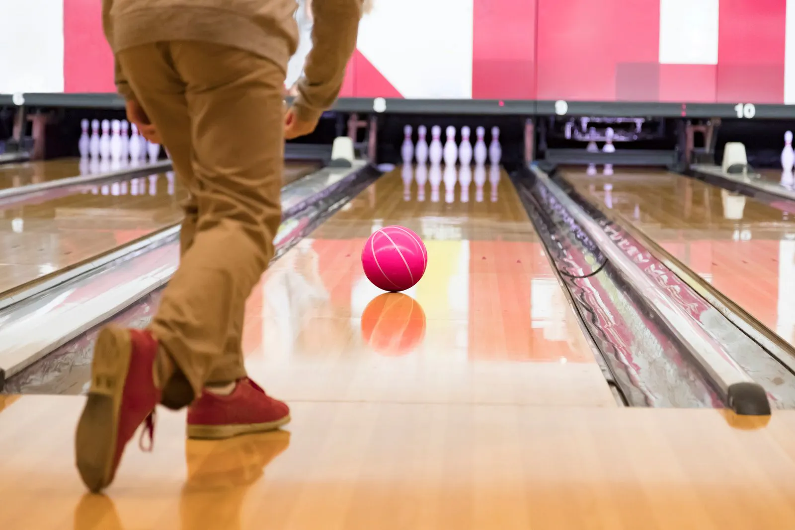 A man throws a bowling ball down a bowling alley