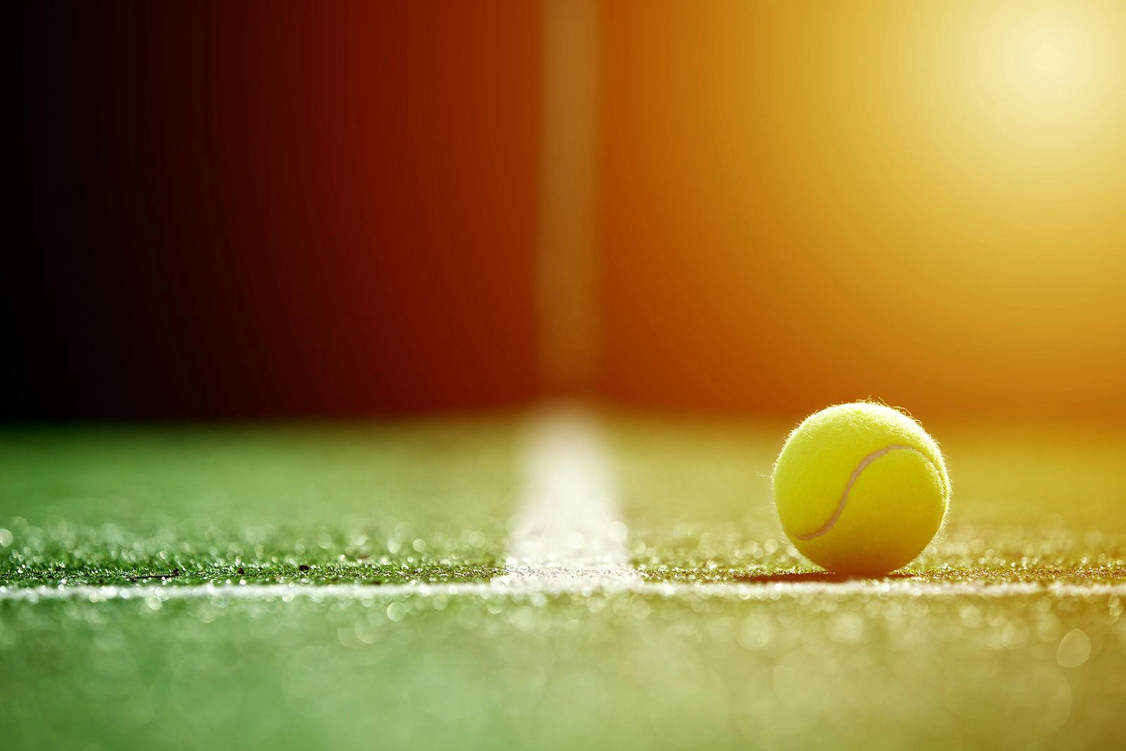 A tennis ball on the lines of a tennis court