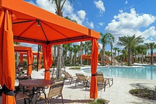 An orange gazebo with chairs and tables by Villatel resort pool