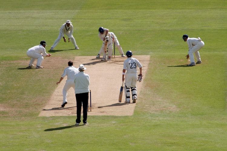 Men and an umpire on a cricket pitch
