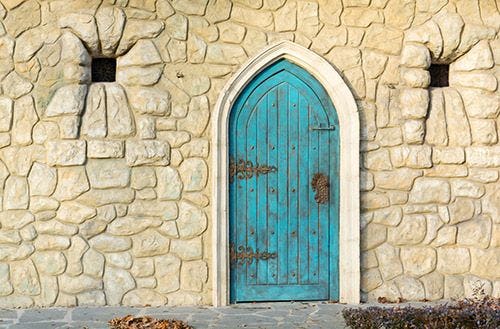 A blue arched door in the stone wall of a castle in Tuscany