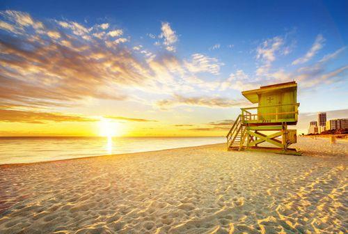 Sunset over a white sand beach and lifeguard hut in Florida