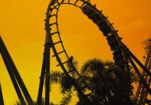 Silhouette of a roller coaster against an orange sky