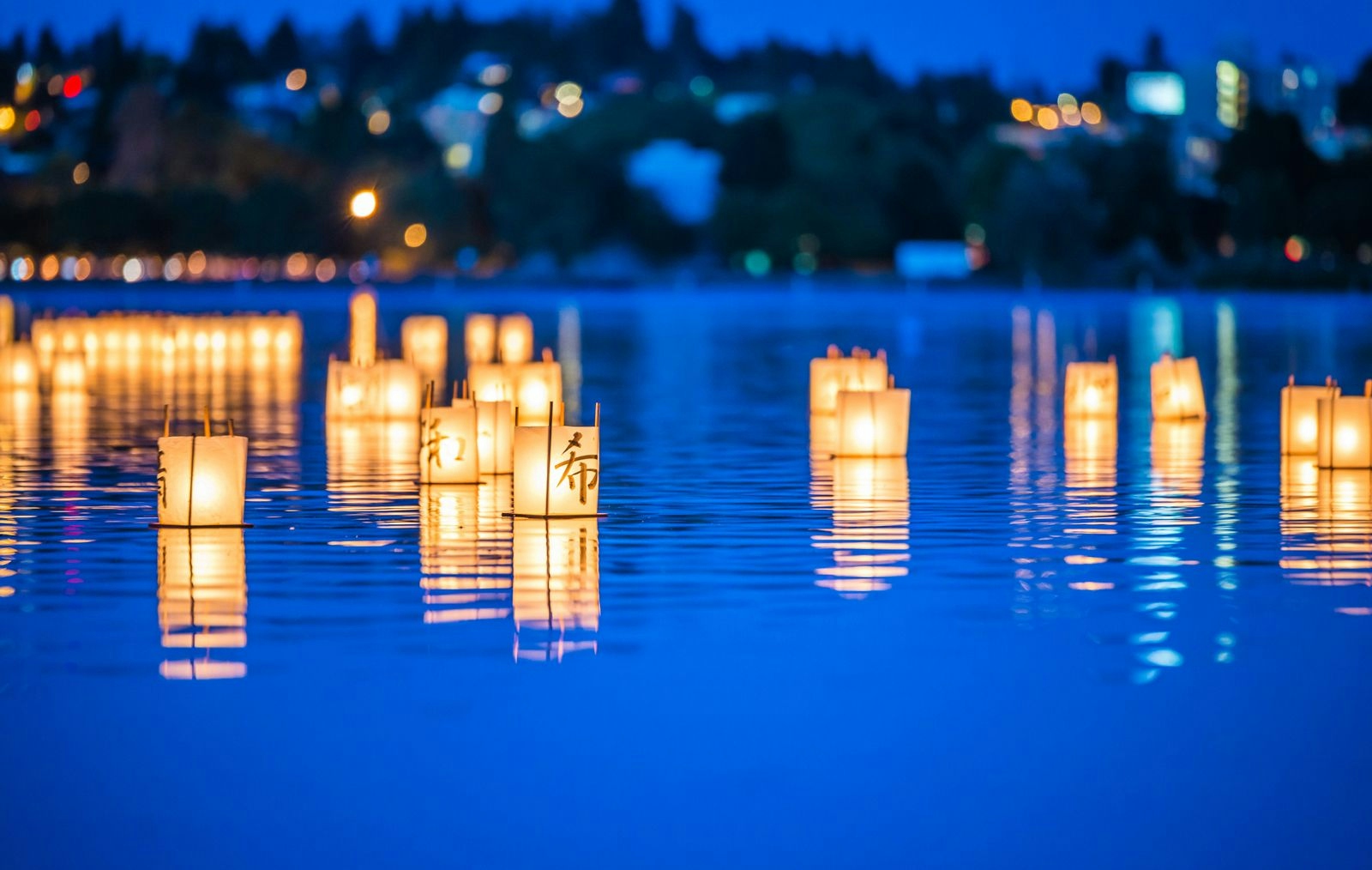 Warm box shaped lanterns floating on still blue water