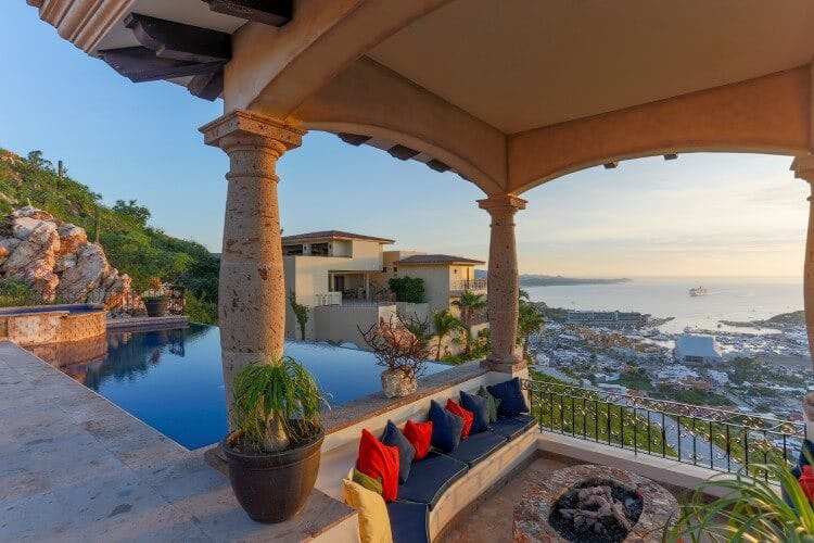 covered seating area with fire pit and pool overlooking land and ocean