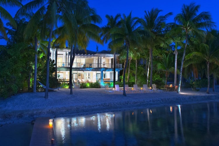 glass fronted villa at dusk on beach with palm trees