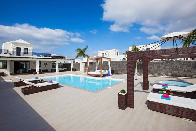 large deck with loungers and pool with white villa in background
