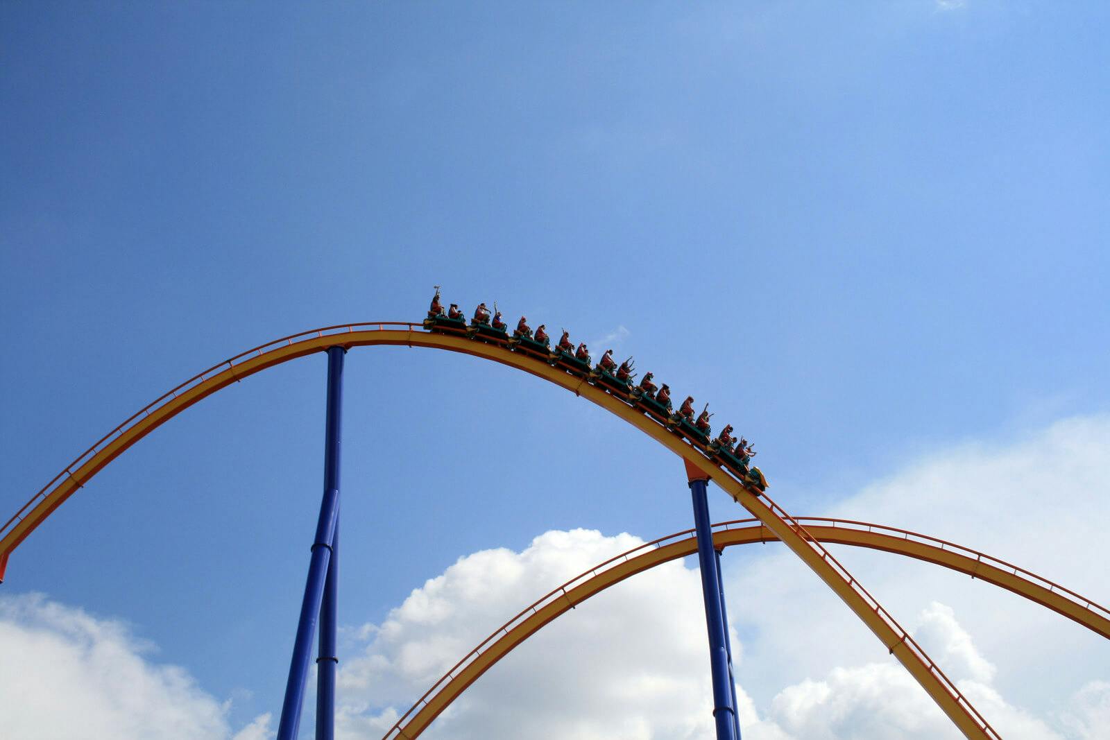 People on a rollercoaster with blue sky behind