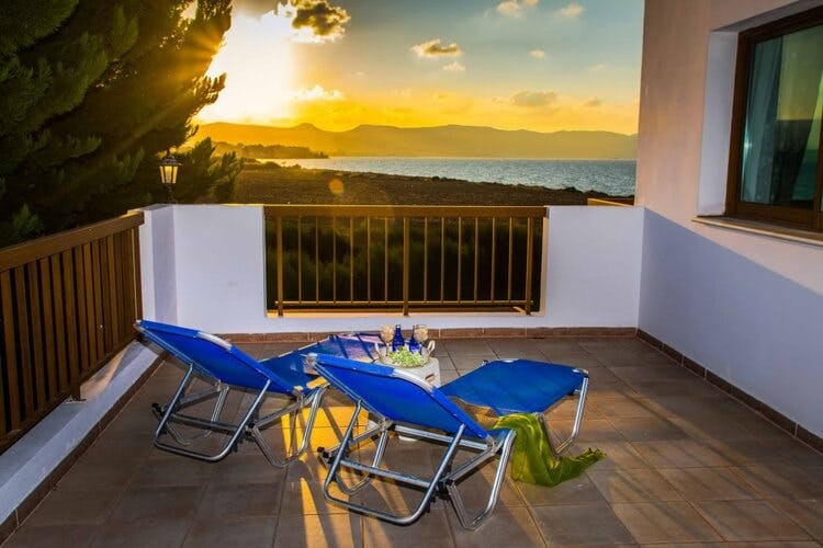 sun loungers on balcony overlooking ocean at sunset