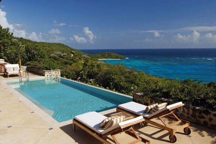 infinity pool and two loungers overlooking ocean