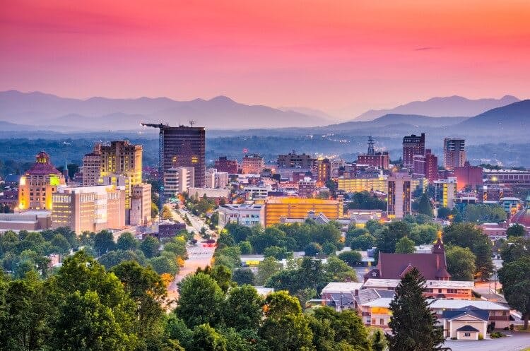 Sunset in Asheville, with the sky glowing pink and illuminated the city skyline