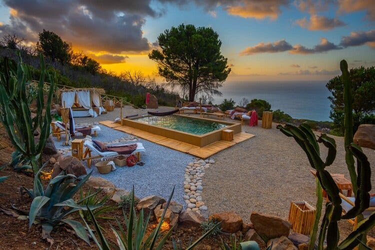 pool and loungers overlooking ocean at dusk
