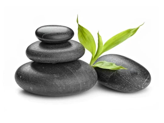 Smooth black massage stones with a leaf