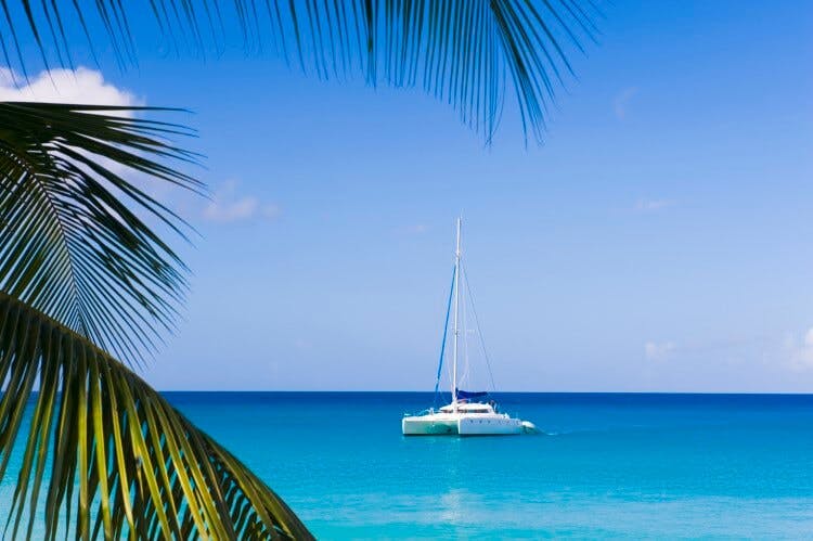 A sailboat on flat blue sea in the Caribbean