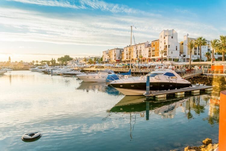 Vilamoura harbor with buildings along the waterfront and small boats floating on still water