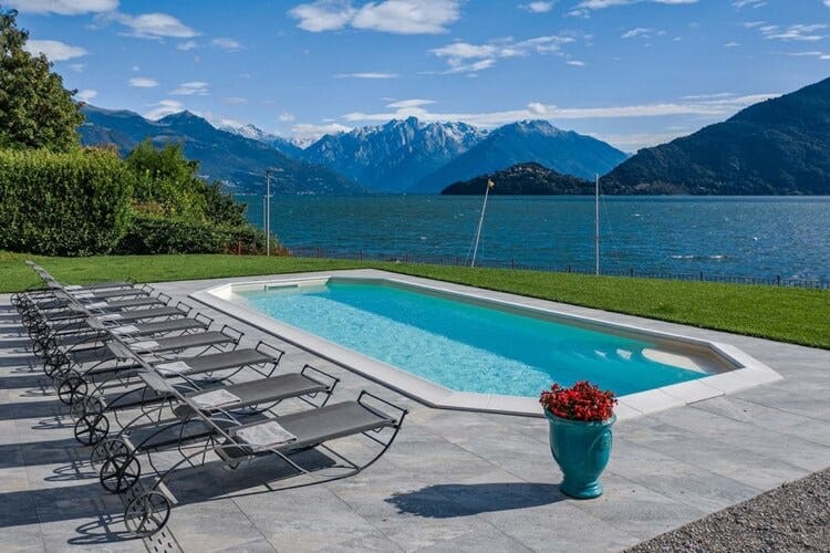 sun loungers and pool with lake and mountains in background